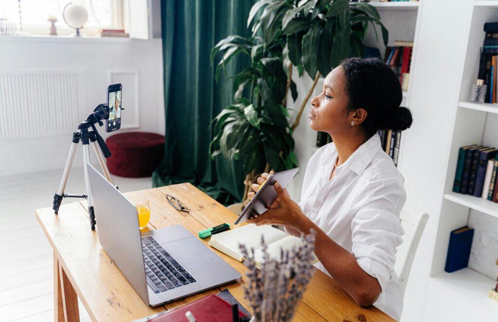 black woman looking at a phone on a tripod participating in content creation