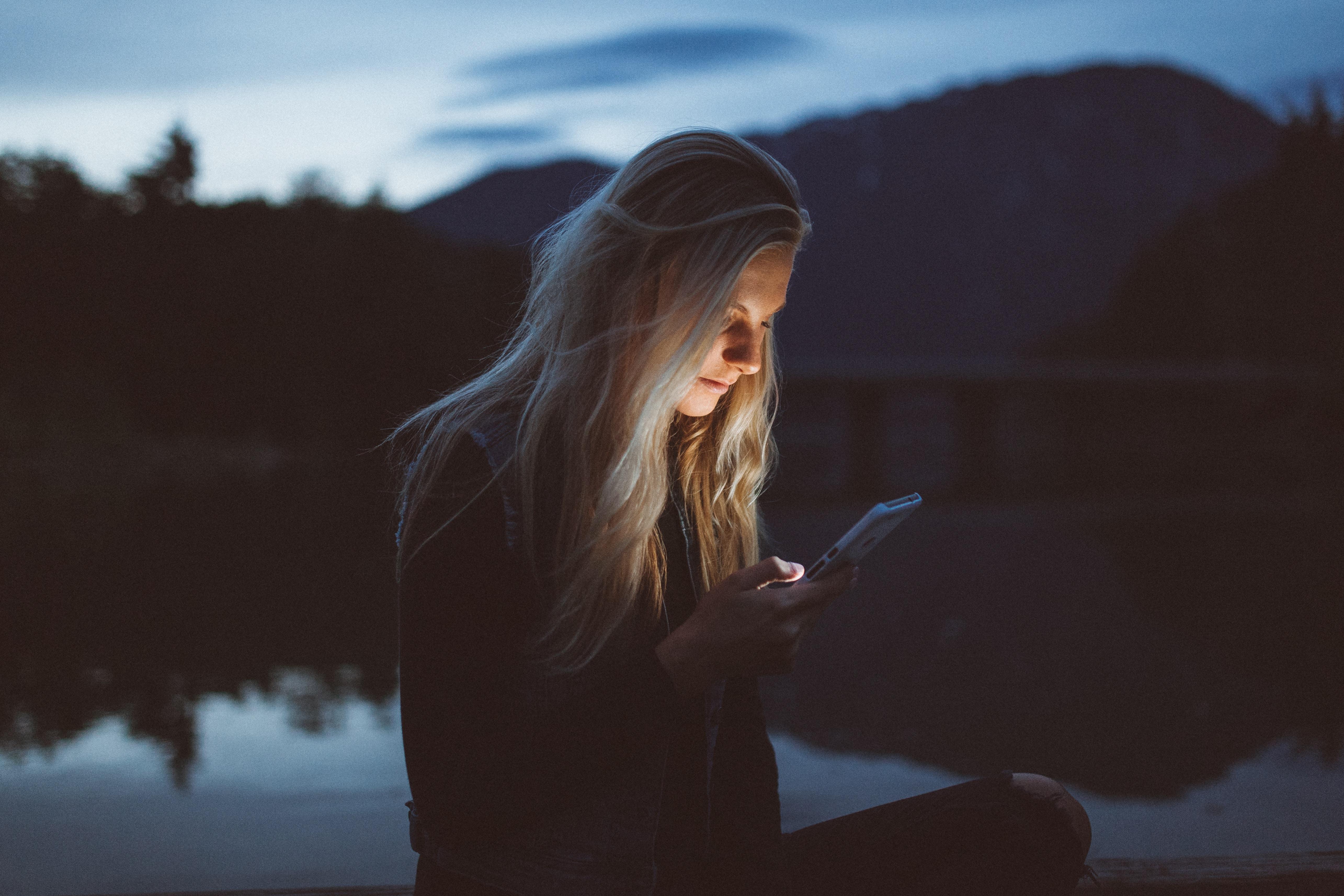 Woman standing outside looking at a cell phone.