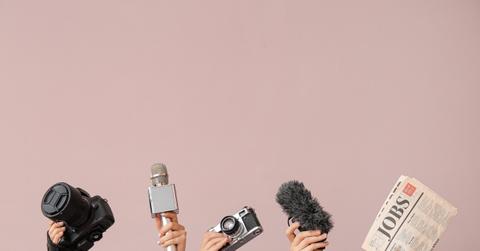 Female hands with newspaper, microphones and photo cameras on color background