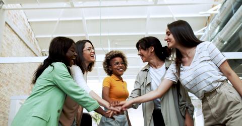 Group of Five multi-ethnic women in an office or coworking shake hands. Empowered women, women entrepreneurs, feminism