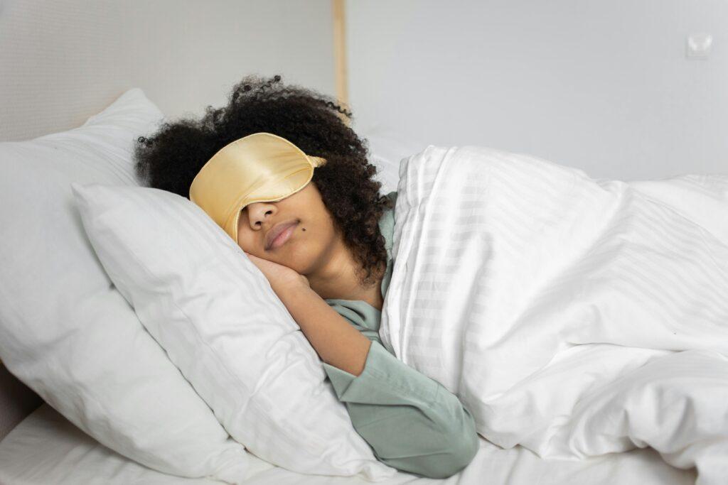 Woman sleeps in bed with sleep mask over eyes