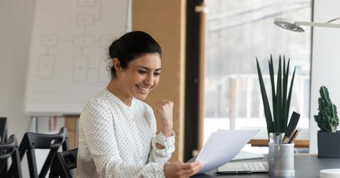 Happy millennial indian woman reading paper letter with good news.